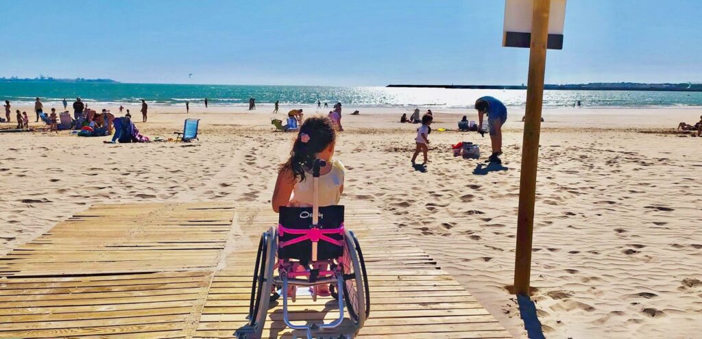 Niña de 7 años en su silla de ruedas en la pasarela playa