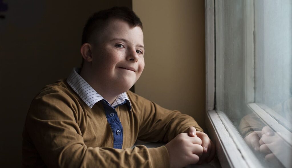 Joven con Síndrome de down en la ventana