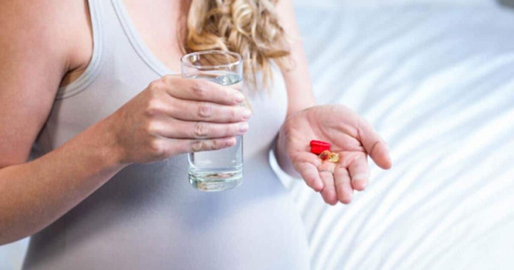 Pregnant woman taking a pill