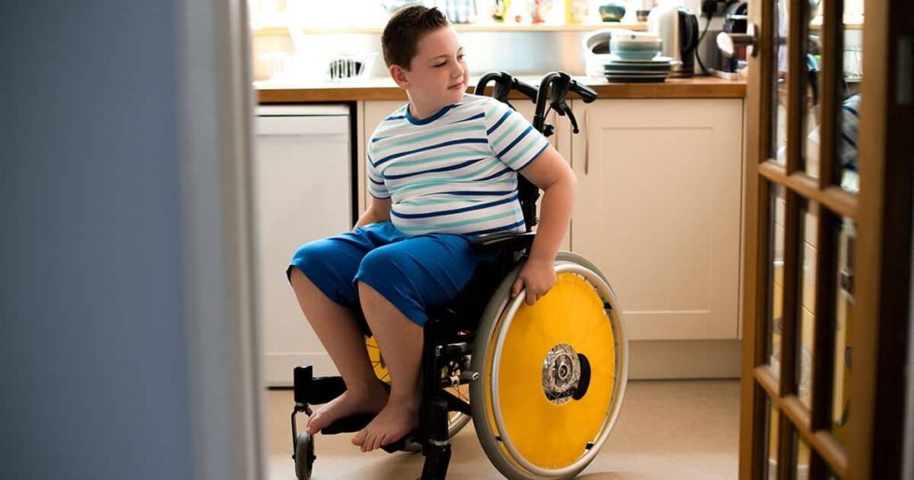 Niño en silla de ruedas en la cocina