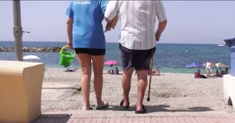 Persona con discapacidad siendo ayudada a entrar en la playa de Adra (Almería)