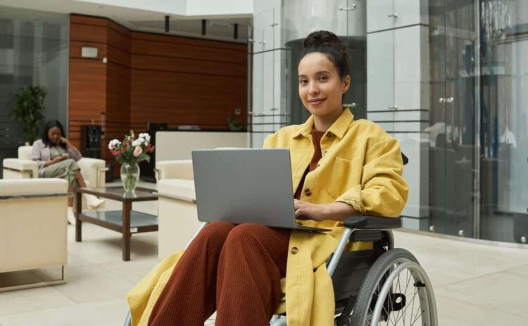 Mujer en silla de ruedas trabajando desde el ordenador portátil