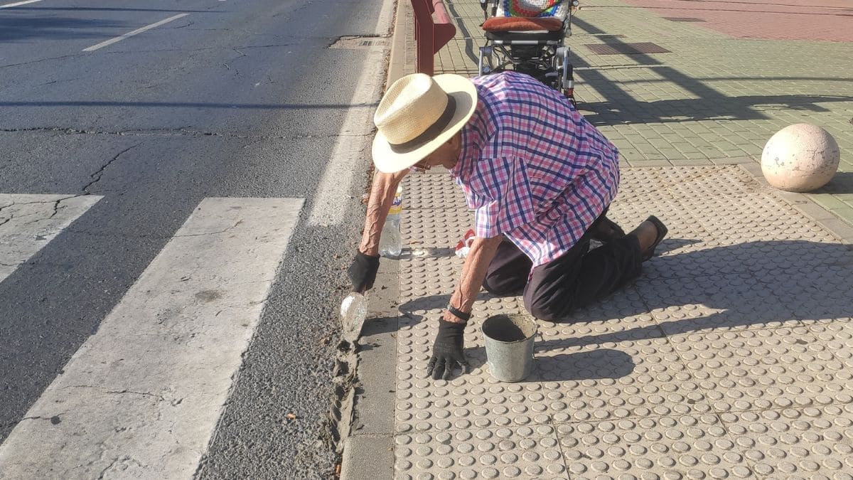 Una persona mayor arregla una acera en Aljaraque (Huelva) para hacerla accesible