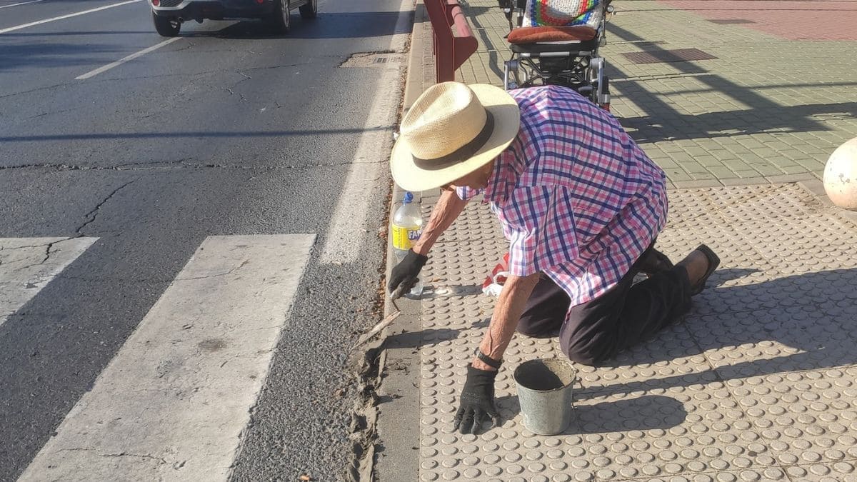 Una persona mayor arregla una acera en Aljaraque (Huelva) para hacerla accesible 